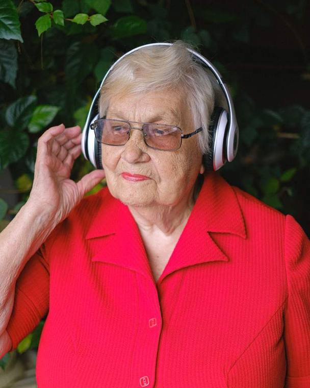 Senhora sorrindo enquanto ouve música com fones de ouvido
